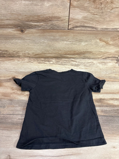 Back view of a plain black H&M toddler t-shirt on a wooden background.