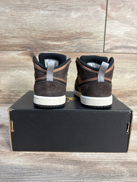 Back view of toddler brown suede high-top sneakers on a black shoe box, wood background