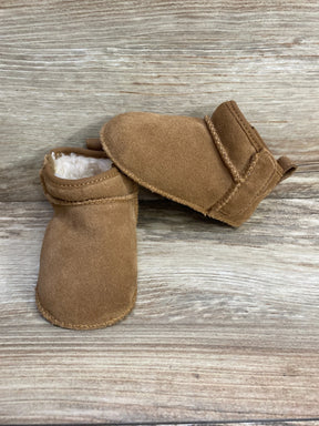 Brown suede baby moccasin slippers with soft white lining on wood surface