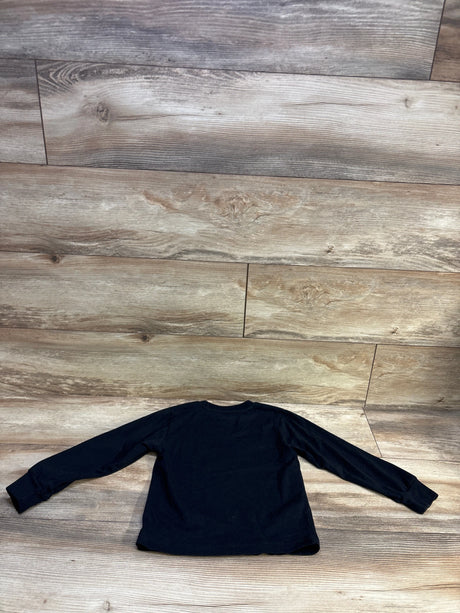 Flat lay of a black Nike long-sleeve shirt in size 4T on a wood-look floor