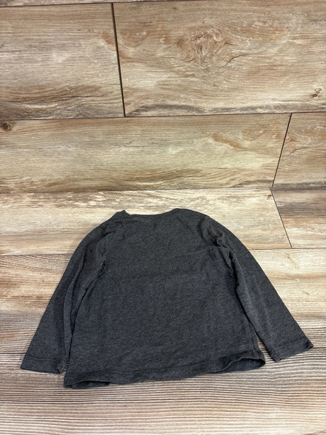 Back view of an Old Navy gray long-sleeve dinosaur shirt in size 2T laid flat on a wood-look floor