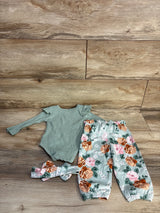 Flat lay of 4pc baby set: green ribbed long-sleeve bodysuit, mint floral elastic-waist pants, matching headband on wood floor