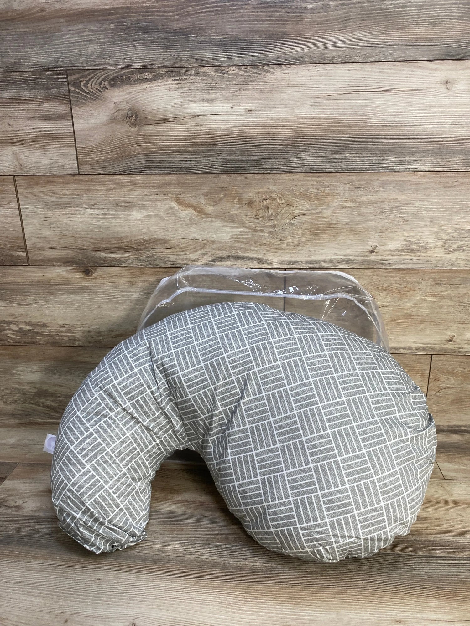 Front-angle view of Boppy Cuddle pregnancy pillow with gray basket weave slipcover showing curved C-shape on wood plank background