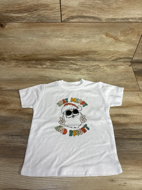 White kids Christmas tee with Santa graphic saying 'Stay Merry and Bright', laid on wood floor