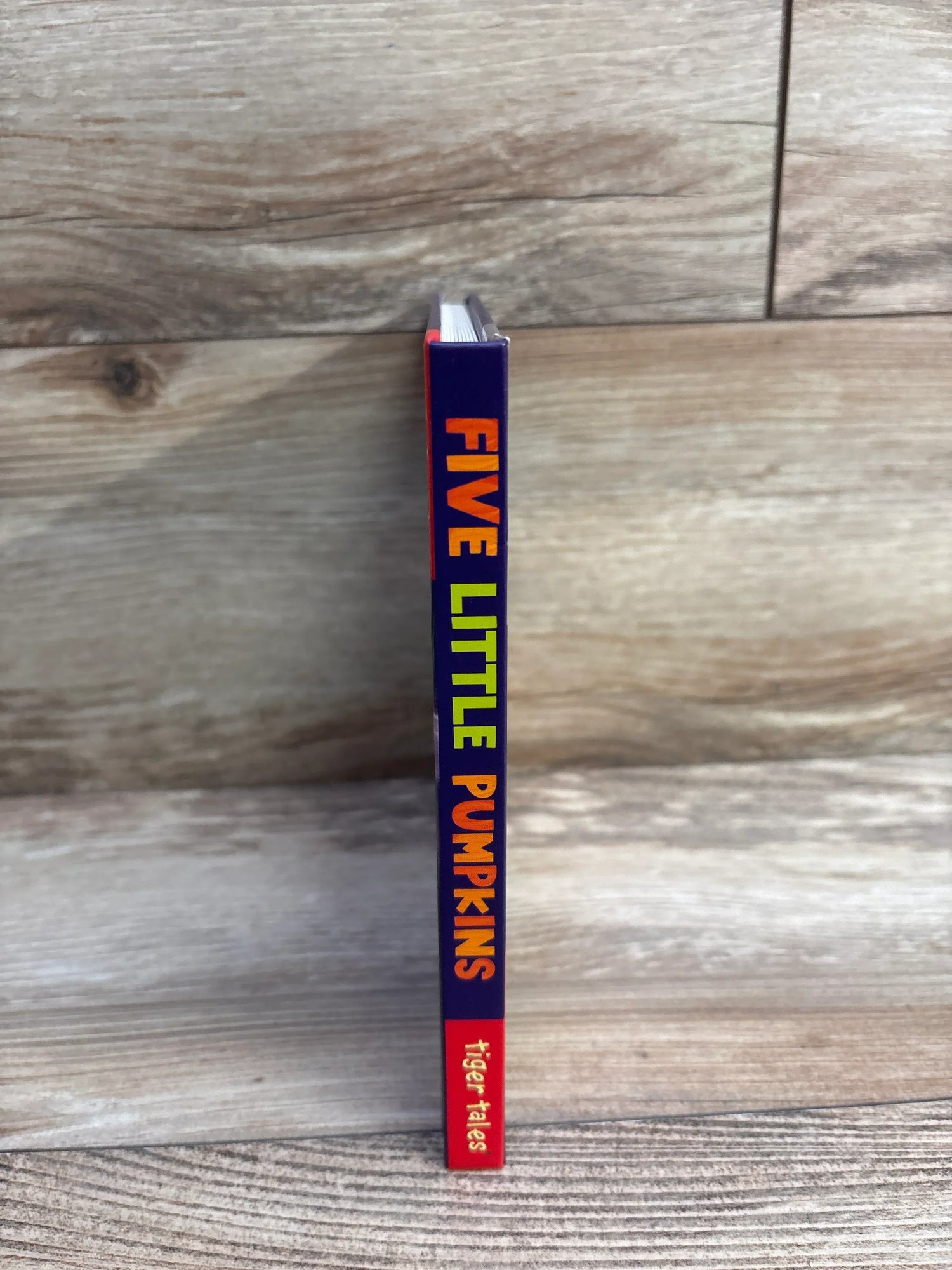 Five Little Pumpkins children's book by Tiger Tales, standing on wood floor
