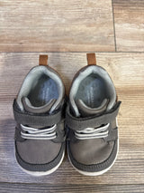 Top view of toddler Munchkin by Stride Rite Miller grey sneakers showing velcro straps and elastic laces on wood floor background