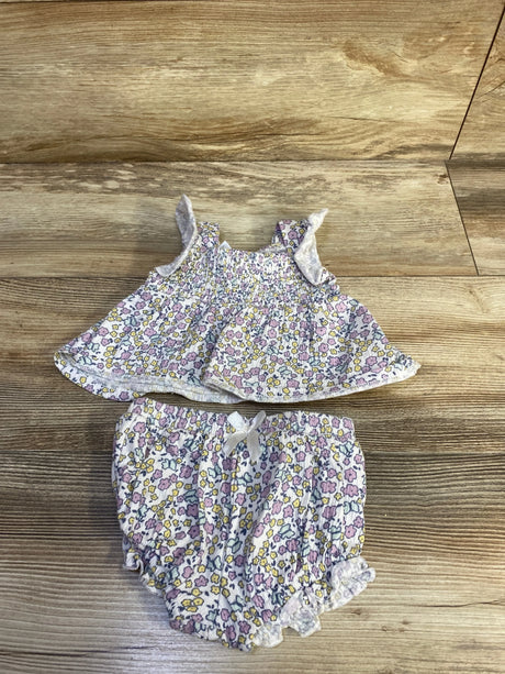Flat lay of 0-3M two-piece smocked floral top and bloomers showing ruffle straps and elasticized legs on wood background