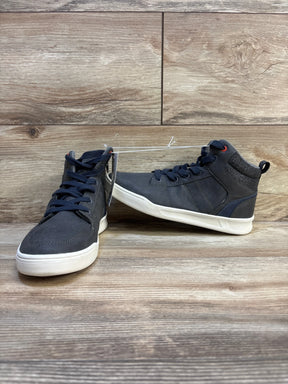 Pair of navy blue high-top kids sneakers with white soles on wood floor