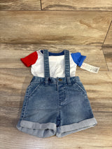 Flat lay of denim suspender shorts with white tee (red and blue sleeves), rolled cuffs and adjustable straps on wood floor, size 3-6M