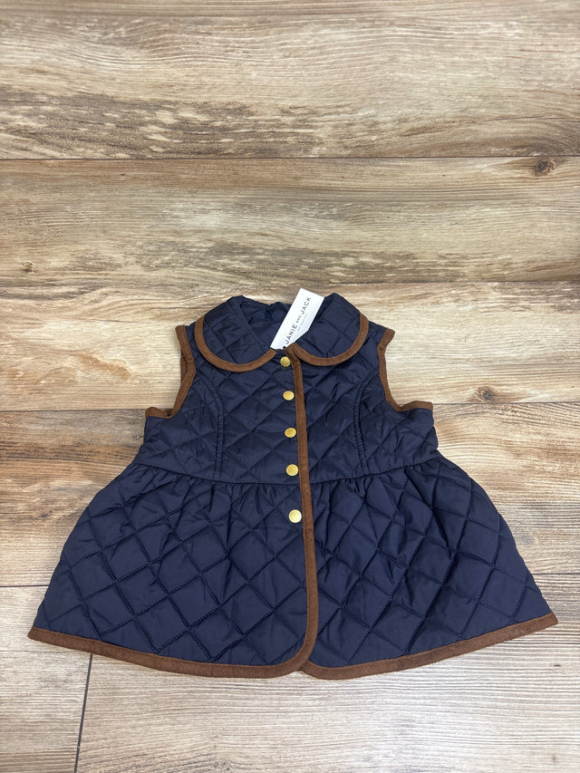 Front view of navy quilted peplum vest showcasing brown trim, rounded collar, gold buttons, and flared hem on wood grain