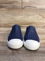 Navy blue slip-on kids shoes with white rubber toe caps, perforated for breathability, on wood floor