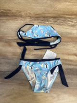 Light blue girls bikini set with beach hut print and navy tie straps on wood background