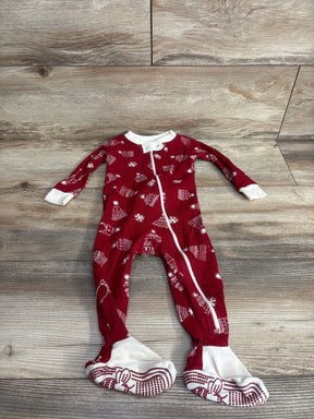 Red holiday-themed baby footed pajamas with snowflake and sweater patterns on wood floor