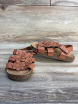 Brown girls sandals with floral accents and cork soles on wood background