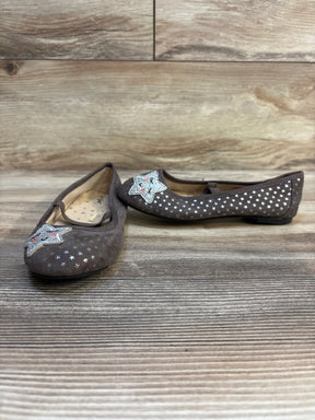 Brown girls' flats with silver star patterns and sequin star accents on wooden floor