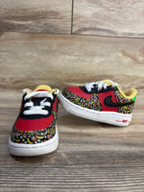 Front and side of Nike Force 1 TD Strawberry Banana shoes showing fruit-print panels, red toe and black Swoosh on wood floor
