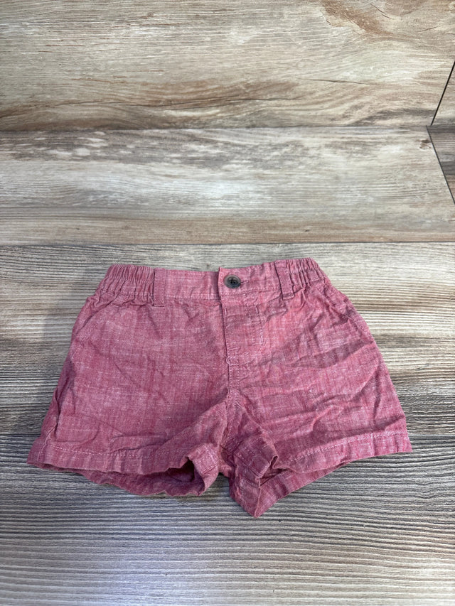 Front view of red Children's Place baby shorts size 0-3M with elastic waistband, single button, rolled cuffs on wood surface