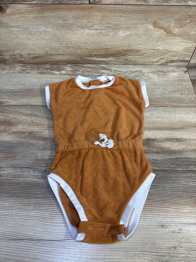 Top-down view of Lila and Jack brown terry bodysuit with white trim, crotch snaps, and small shell patch on wood background