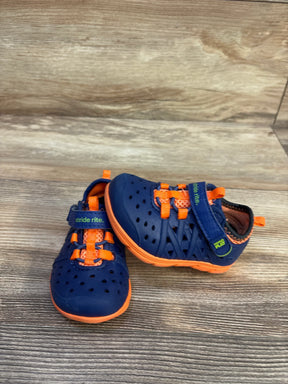Angled front view of Stride Rite Phibian toddler water shoes, navy with orange accents, perforated upper and elastic laces on wood background