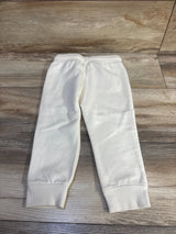 Back view of cream Oshkosh fleece toddler joggers showing elastic waistband and cuffed ankles on wood floor