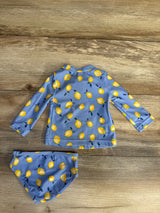Flat lay of blue 2-piece lemon-print rashguard and matching bikini bottoms showing back view on wood background