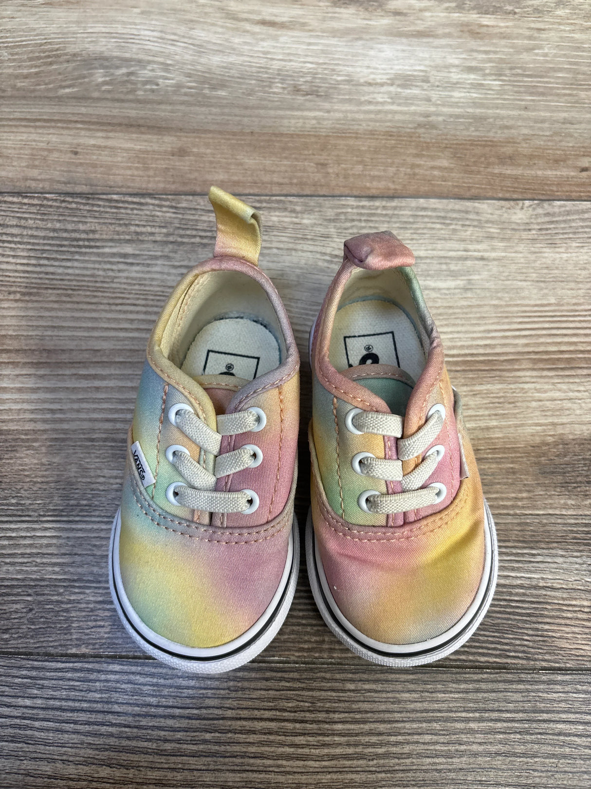 Pastel tie-dye baby sneakers with white laces on wood floor