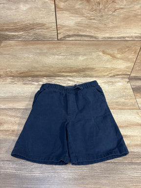 Navy blue kids shorts with elastic waistband, laid flat on wood floor