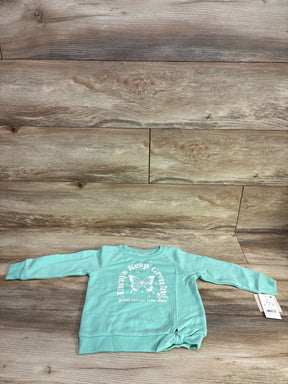 Mint green toddler sweatshirt with butterfly and positive growth text, laid flat on wood