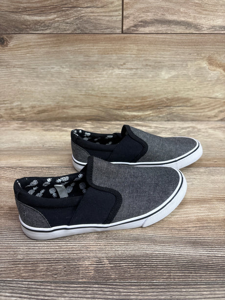 Side view of Cat & Jack gray canvas slip-on sneakers showcasing black elastic panels and pineapple-print lining on wood flooring
