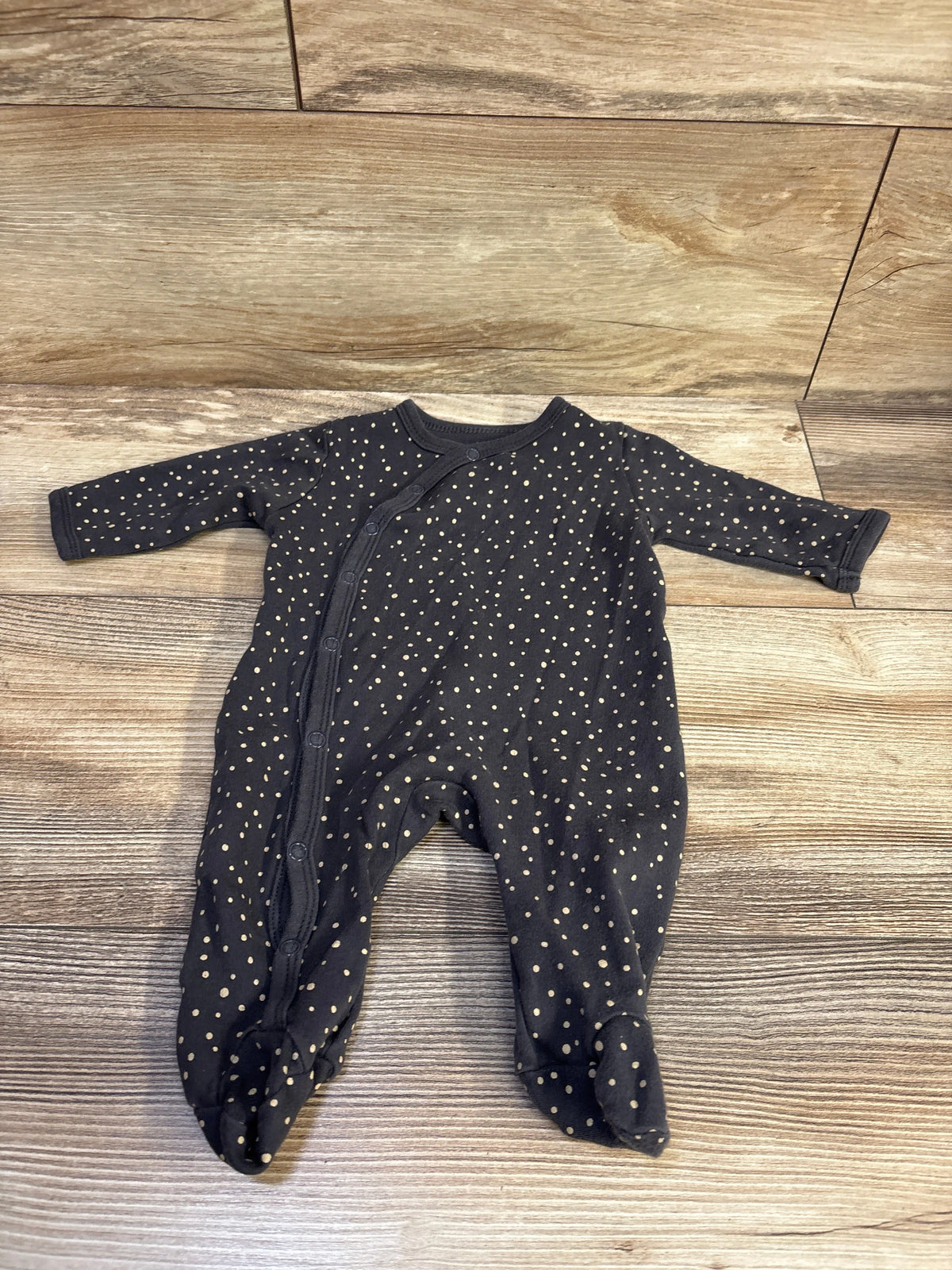 Front view of a Side Snap Sleeper with long sleeves, footed legs, and cream polka dots on a wood floor