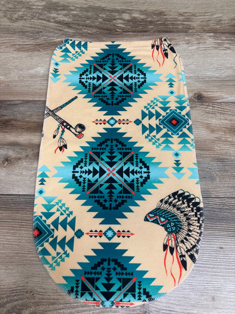 Front view of beige Native Design Swaddle Sack showcasing geometric and feather print with wood background