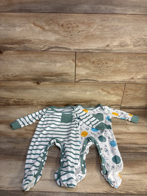 Top-down view of two newborn footed coveralls (2-pack) showcasing a green-striped coverall with chest pocket and a space-print coverall on wood background