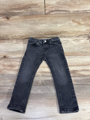 Black children's skinny jeans with front pockets on wooden floor background