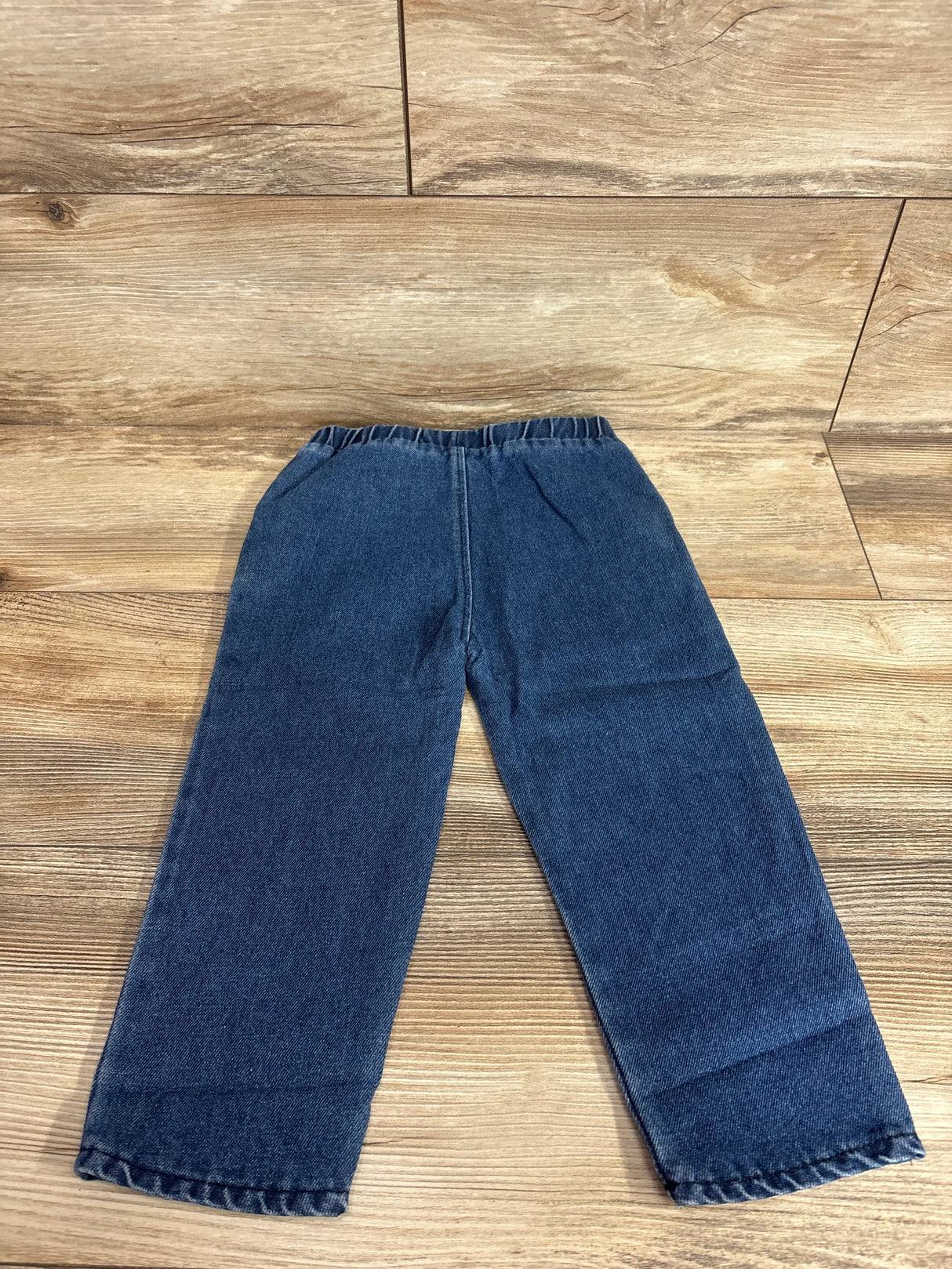 Flat lay of blue T-Rex toddler jeans size 2-3Y showing elastic waistband and straight legs on wood floor