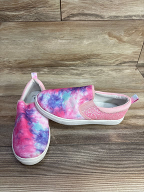 Kids slip-on sneakers with pink, purple, and blue tie-dye pattern and glitter detail on wooden floor
