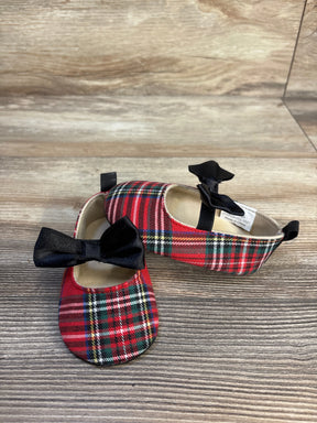 Red plaid baby shoes with black bows on wooden background