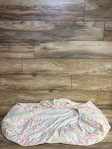 Top-down view of Cloud Island fitted crib sheet showing pastel rainbow arches on white fabric with elastic edges on wood floor