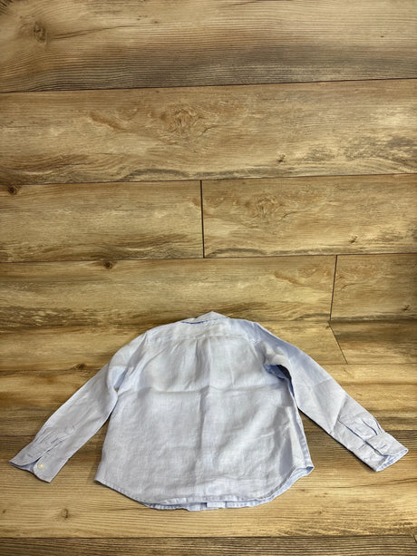 Back view of boys' light blue linen long-sleeve shirt showing button cuffs and curved hem on wood floor