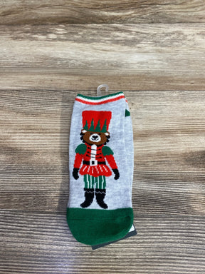 Gray sock with green toe featuring a colorful bear dressed as a nutcracker soldier on a wooden surface