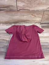 Back view of OshKosh maroon short-sleeve hooded shirt size 5T showing hood and white side stripe on wooden floor background
