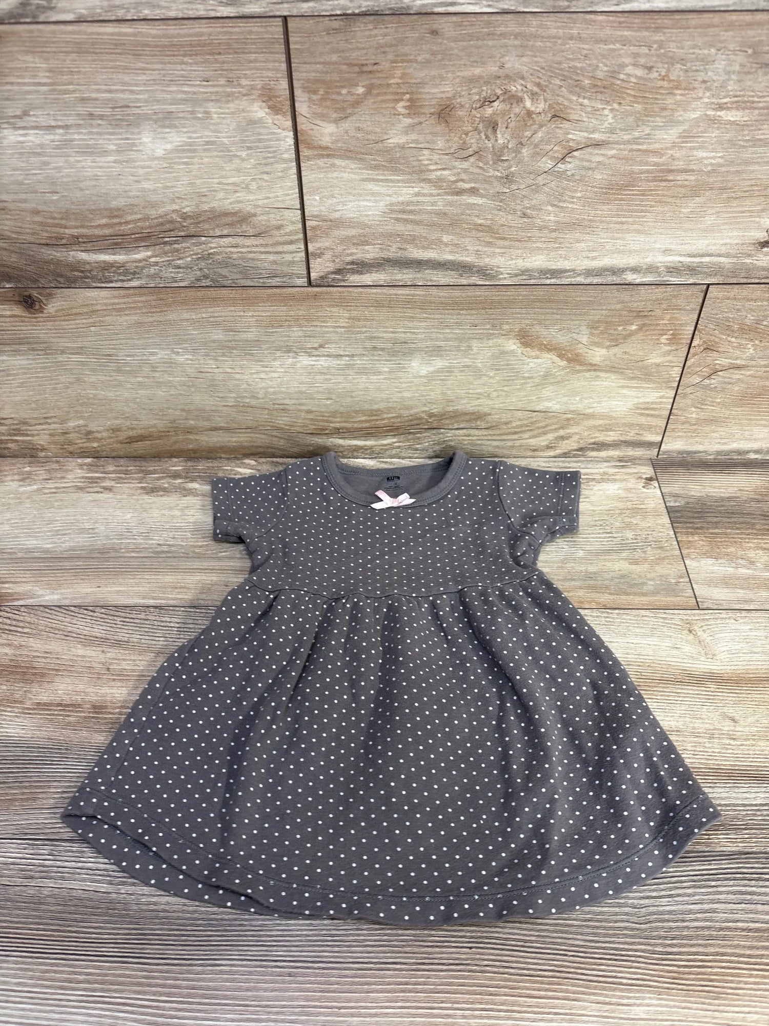 Flat lay of Hudson Baby brown polka dot 18-month dress showcasing short sleeves and gathered skirt on wood plank background