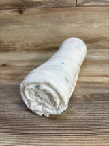 Rolled white muslin baby swaddle blanket with subtle print on wood background