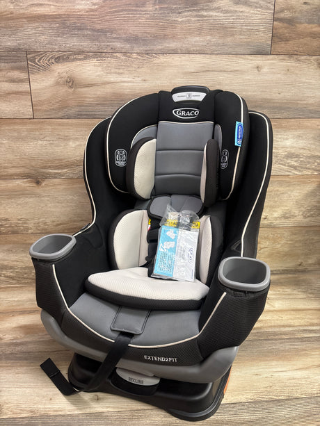Front view of Graco Extend2Fit convertible car seat in Gotham showcasing cup holders and padded seat with wood floor background