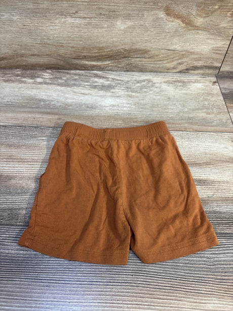 Flat lay of The 5th Legacy caramel brown toddler shorts (18-24 months) showing elastic waistband and straight hem on wood background