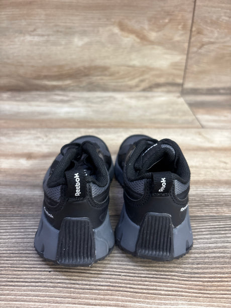 Rear view of Reebok Charge Run sneakers in black, size 6C, showcasing textured heel panels on a wood-grain floor