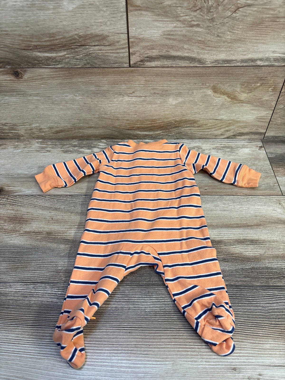 Front view of Carter’s orange and navy striped footed sleeper with long sleeves on a wood-look floor