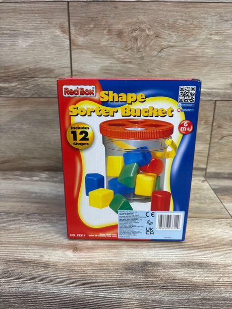 Front view of Red Box Shape Sorter Bucket packaging showing 12 colorful shapes with a wood-patterned background
