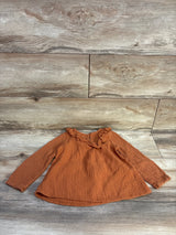 Flat lay of caramel Tahari gauze long-sleeve shirt 4T showing ruffled collar and smocked cuffs on wood background