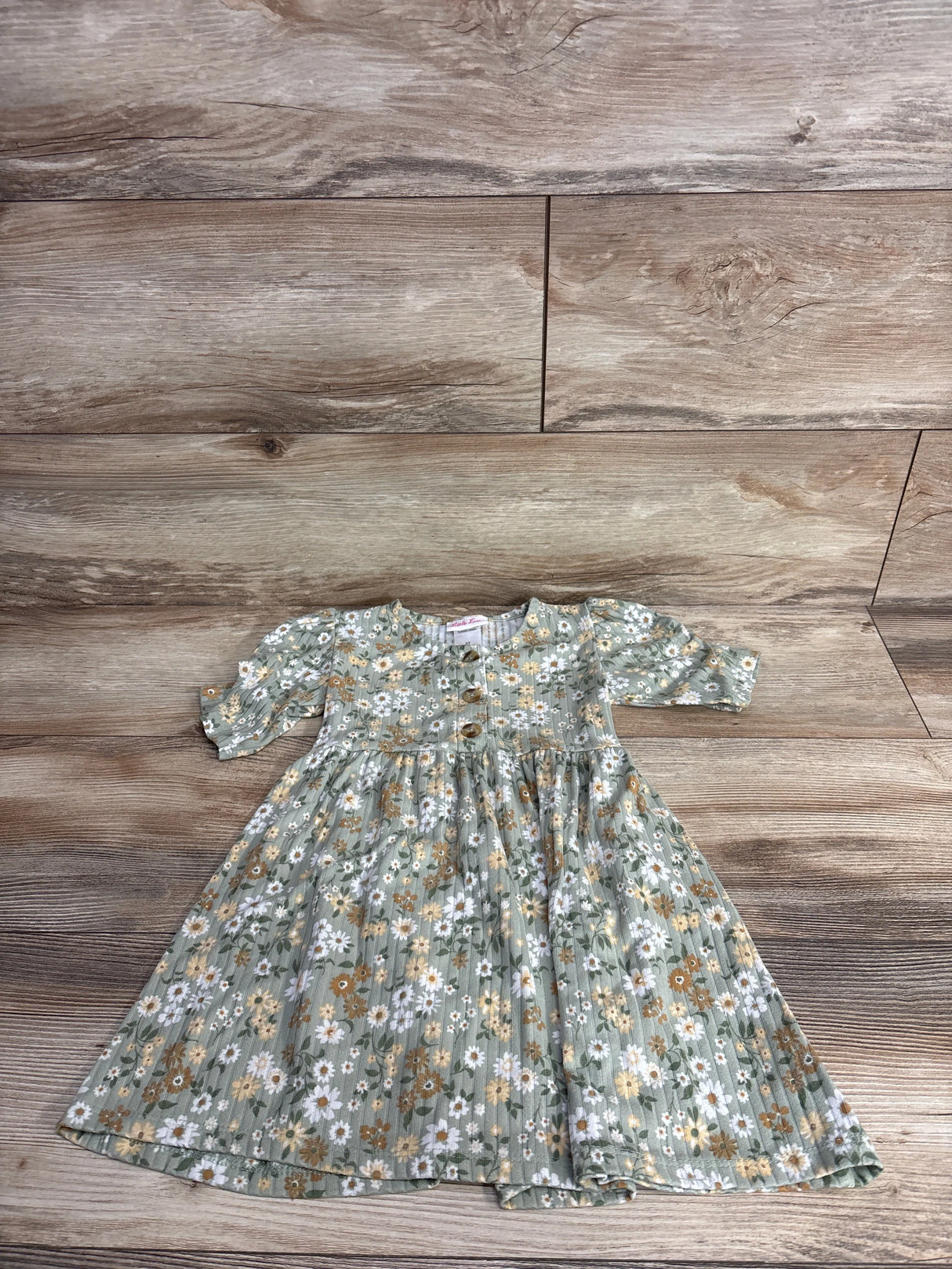 Green floral toddler dress with buttons and 3/4 sleeves on wood background