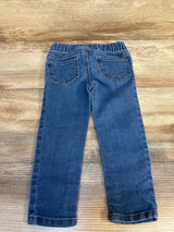 Back view of children's blue denim jeans with elastic waistband on wood background